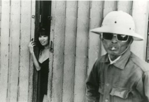 René BURRI - Photography - A prostitute standing at the entrance to a Saigon bordello.